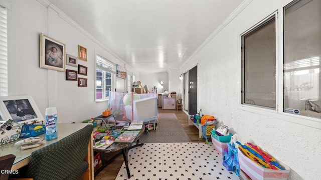 hallway featuring a textured wall, ornamental molding, and wood finished floors