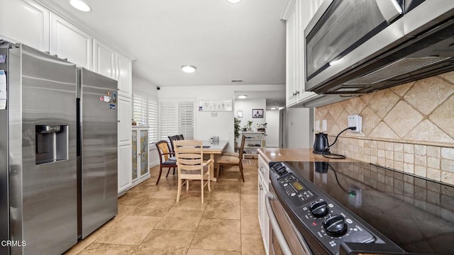 kitchen featuring light tile patterned floors, white cabinetry, stainless steel appliances, and backsplash