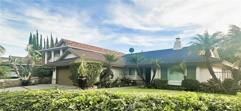 view of front of house featuring a garage, a chimney, concrete driveway, and stucco siding