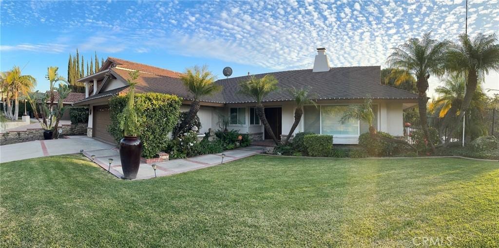 ranch-style home with a garage, driveway, a front lawn, and stucco siding