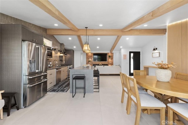 kitchen featuring vaulted ceiling with beams, dark countertops, appliances with stainless steel finishes, a sink, and modern cabinets