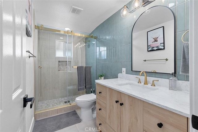 full bathroom with tile patterned flooring, tile walls, a shower stall, and vanity