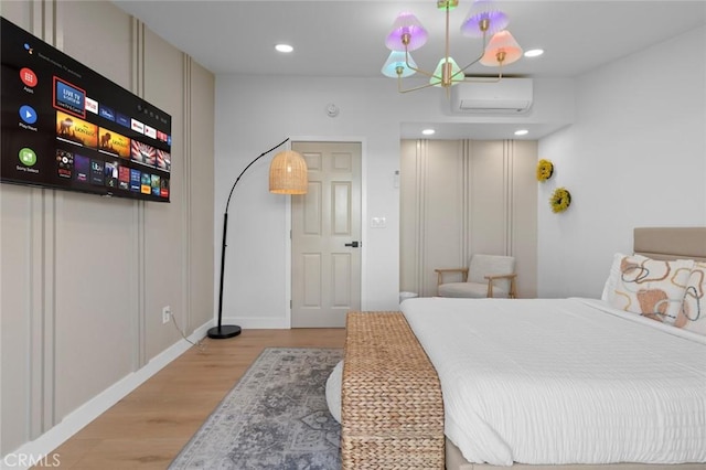 bedroom featuring baseboards, an AC wall unit, light wood-type flooring, and recessed lighting