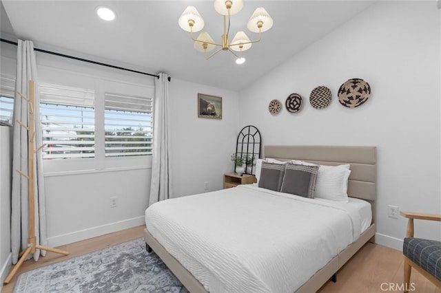 bedroom featuring lofted ceiling, baseboards, a chandelier, and wood finished floors