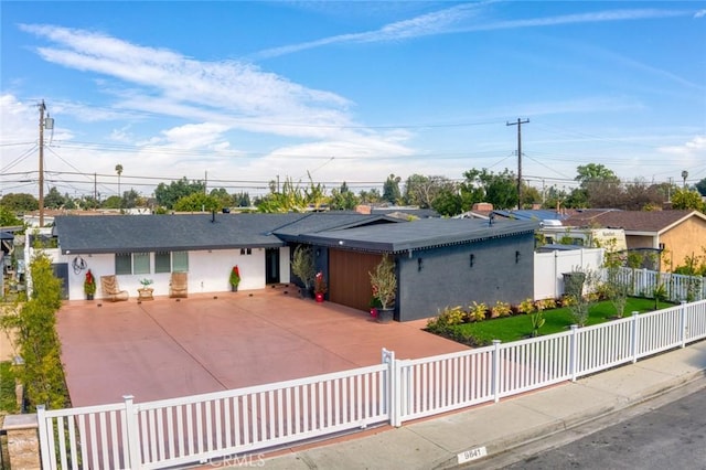 ranch-style home with driveway and a fenced front yard