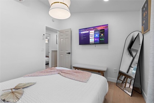 bedroom featuring light wood-style floors, lofted ceiling, and baseboards