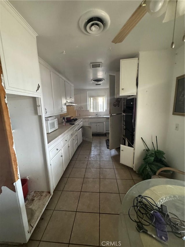 kitchen with white cabinetry, stainless steel appliances, and dark tile patterned floors