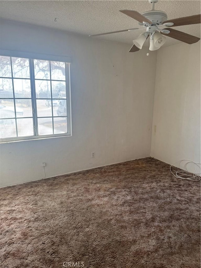 spare room with a textured ceiling, carpet flooring, and ceiling fan