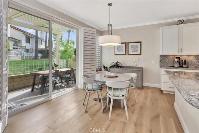 dining room with light wood-type flooring, baseboards, and ornamental molding