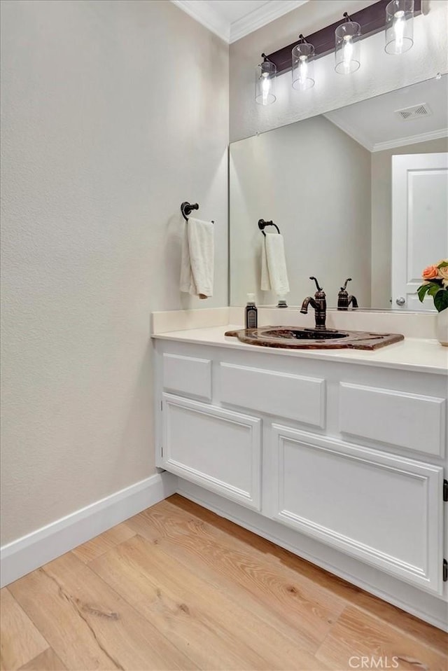 bathroom with ornamental molding, vanity, baseboards, and wood finished floors