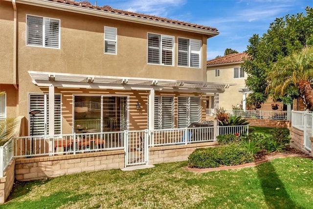 back of house with a lawn, fence, a pergola, and stucco siding