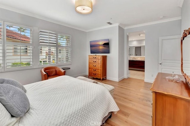 bedroom with crown molding, light wood-style flooring, baseboards, and ensuite bath