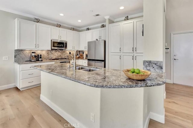 kitchen featuring light stone counters, a sink, white cabinets, ornamental molding, and appliances with stainless steel finishes