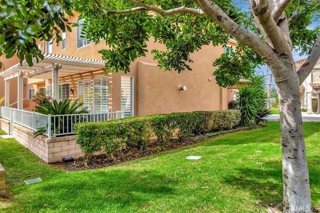 view of property exterior with a pergola, a lawn, and stucco siding