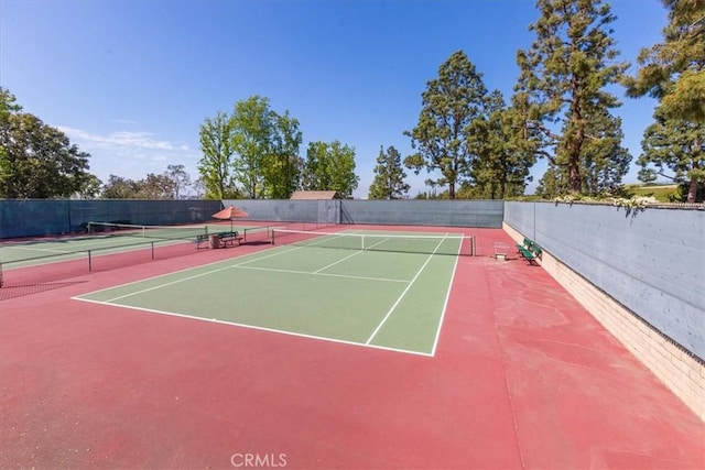 view of tennis court with community basketball court and fence