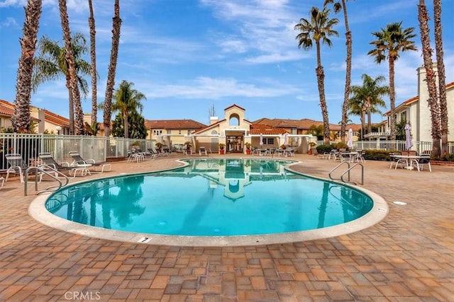 community pool featuring a patio, fence, and a residential view