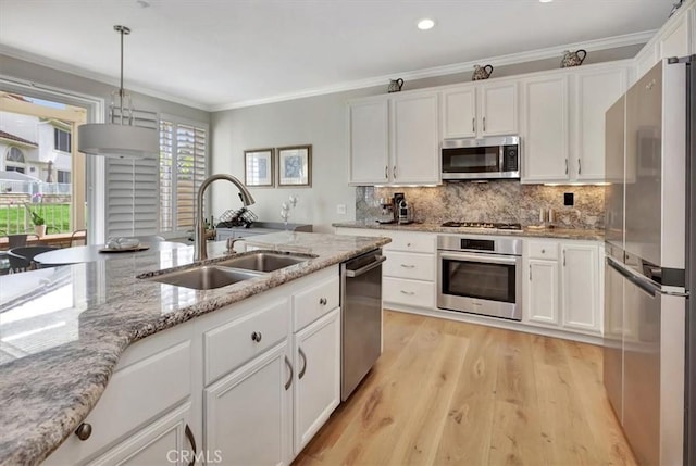 kitchen featuring stainless steel appliances, a sink, white cabinets, backsplash, and crown molding