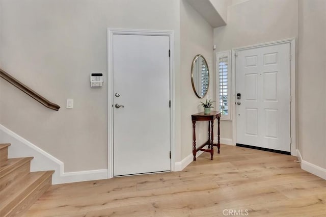 foyer entrance featuring stairway, wood finished floors, and baseboards