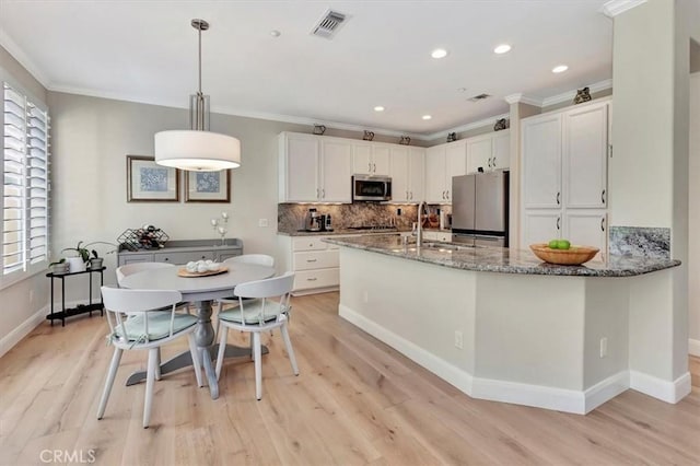 kitchen with ornamental molding, light stone countertops, stainless steel appliances, white cabinetry, and a sink