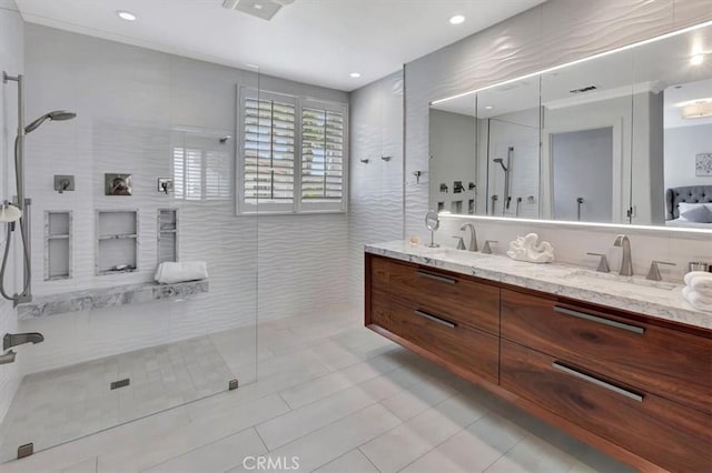 bathroom featuring double vanity, tile walls, a walk in shower, and a sink