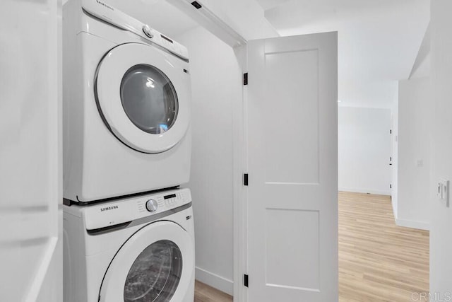 washroom with stacked washer / drying machine and light hardwood / wood-style flooring