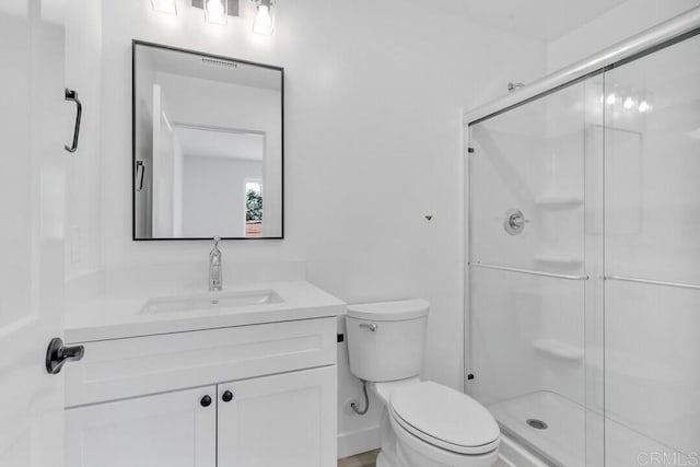 bathroom featuring toilet, a shower with door, and vanity