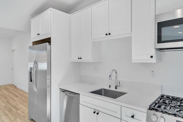 kitchen with sink, white cabinetry, stainless steel appliances, and light hardwood / wood-style flooring