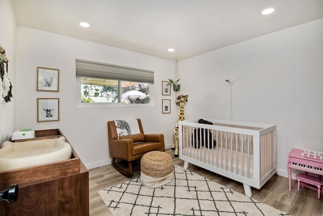 bedroom featuring light wood-type flooring and a nursery area