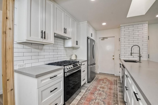 kitchen featuring hardwood / wood-style floors, sink, backsplash, appliances with stainless steel finishes, and white cabinets