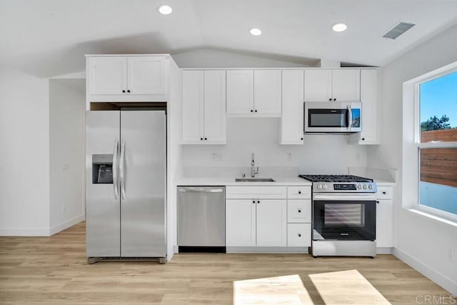 kitchen featuring white cabinets, appliances with stainless steel finishes, sink, and lofted ceiling