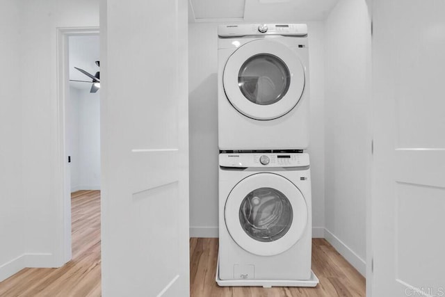 laundry room featuring stacked washer and dryer and light wood-type flooring