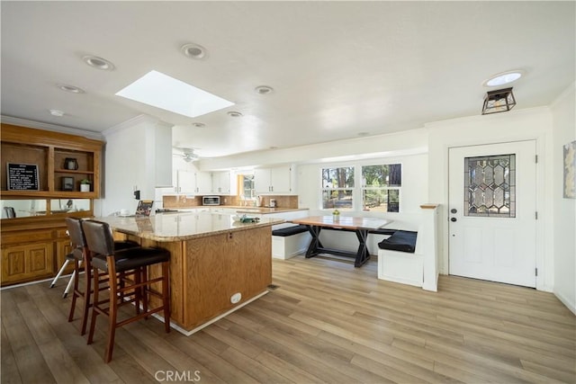 188 S Finch Dr, Big Bear Lake, CA 92315 - kitchen featuring a peninsula, ornamental molding, light wood-style flooring, a skylight, and a kitchen breakfast bar