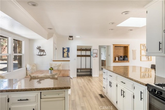 188 S Finch Dr, Big Bear Lake, CA 92315 - kitchen with a skylight, light wood finished floors, dark stone countertops, white cabinetry, and black gas stove