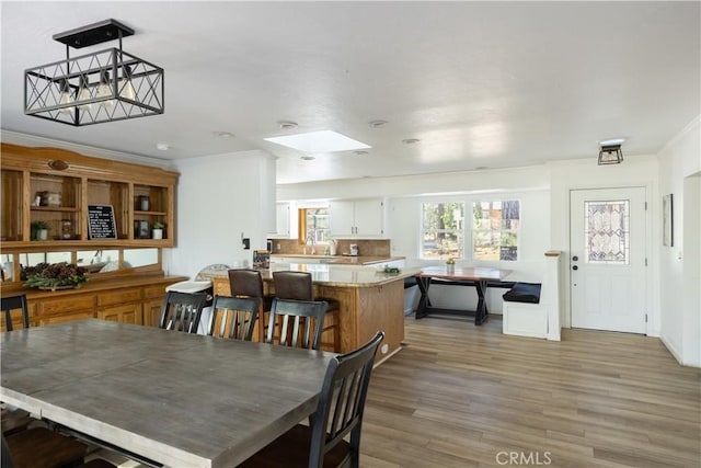 dining area featuring crown molding, a skylight, and hardwood / wood-style floors