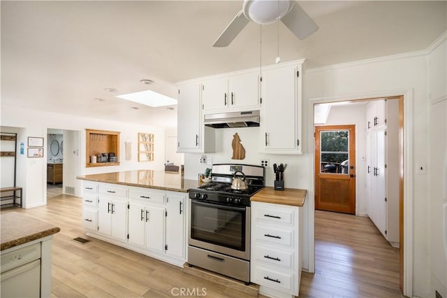 188 S Finch Dr, Big Bear Lake, CA 92315 - kitchen featuring stainless steel gas range oven, under cabinet range hood, light wood-type flooring, a skylight, and white cabinetry