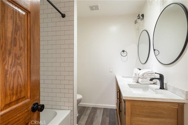 full bathroom featuring toilet, vanity, tiled shower / bath, and wood-type flooring