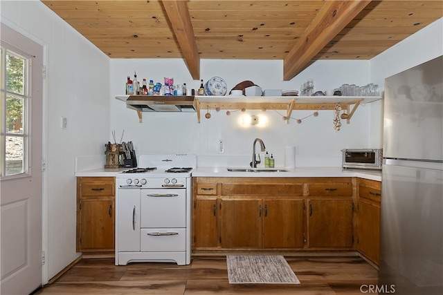 kitchen featuring white gas range, sink, beamed ceiling, and stainless steel fridge