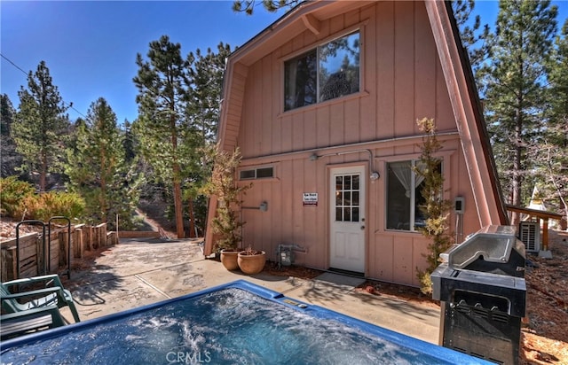 rear view of house with a patio area and a hot tub