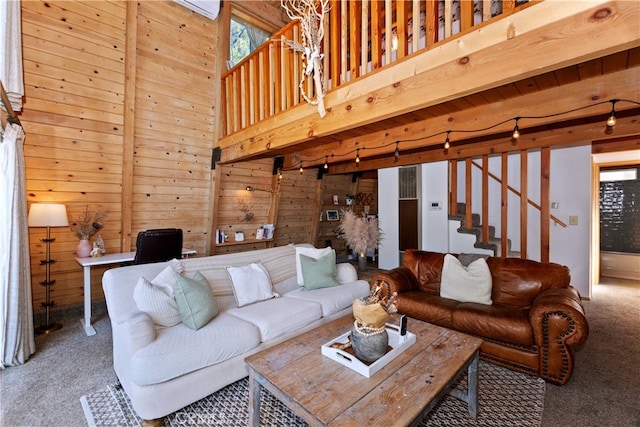 living room with a high ceiling, carpet floors, and wood walls