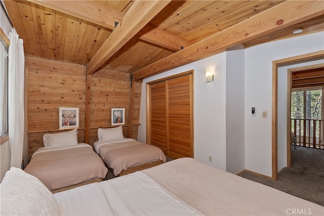 bedroom featuring beam ceiling, carpet flooring, a closet, wooden walls, and wood ceiling