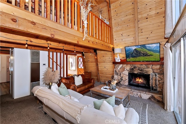 carpeted living room featuring a fireplace, a towering ceiling, wood walls, and a healthy amount of sunlight