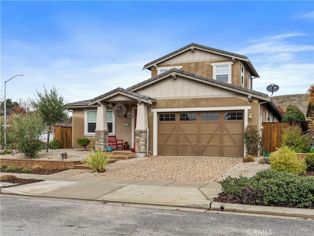 craftsman-style house featuring fence, a tiled roof, stucco siding, decorative driveway, and a garage