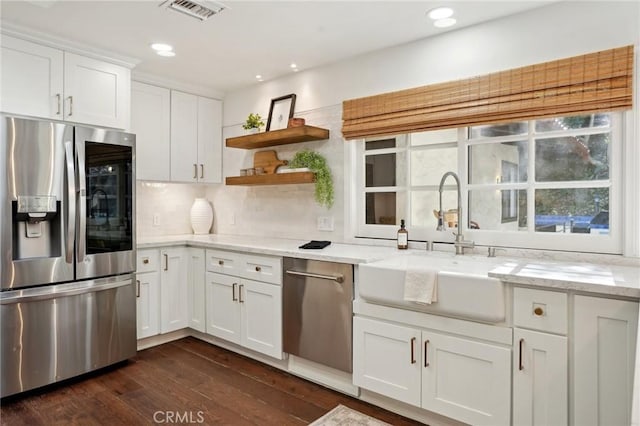 kitchen with white cabinets, visible vents, light stone counters, and stainless steel appliances