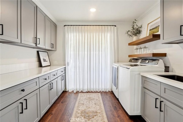 laundry area with dark wood-type flooring, washer and dryer, cabinet space, and crown molding