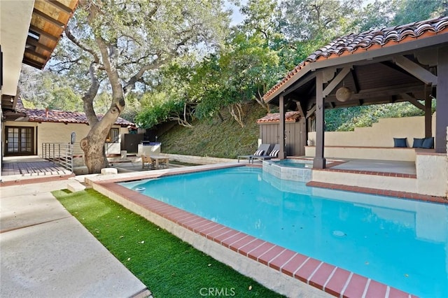 outdoor pool with a patio and an in ground hot tub