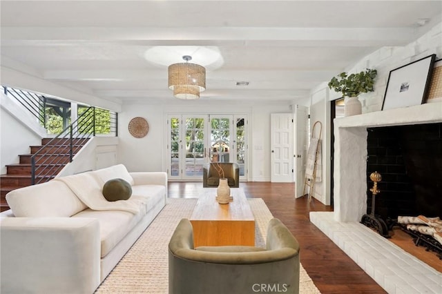 living room featuring stairs, beam ceiling, a healthy amount of sunlight, and wood finished floors