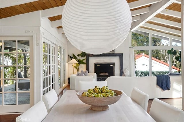 sunroom with vaulted ceiling with beams, wooden ceiling, and a fireplace