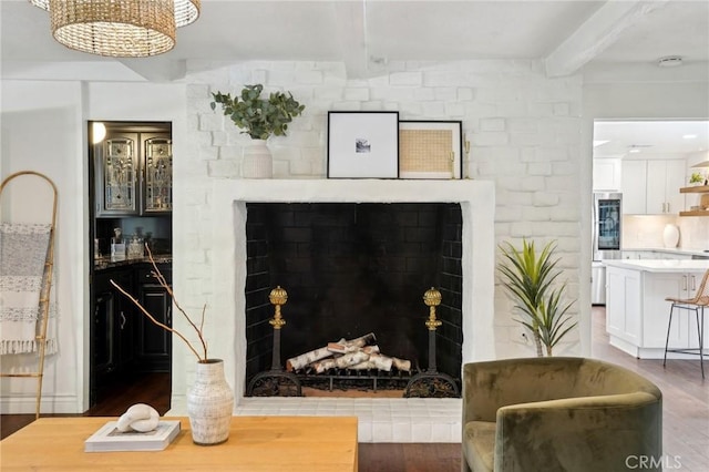 interior space with light wood-style floors, a fireplace with raised hearth, and beamed ceiling