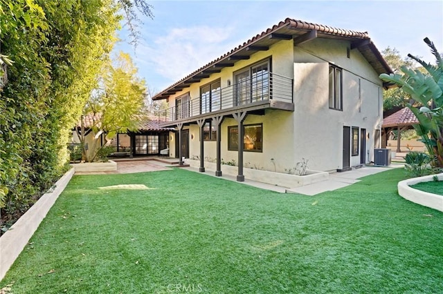 back of property with a lawn, a patio, a tile roof, central AC, and stucco siding