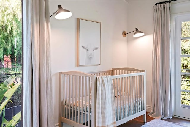 bedroom featuring a crib and dark wood finished floors